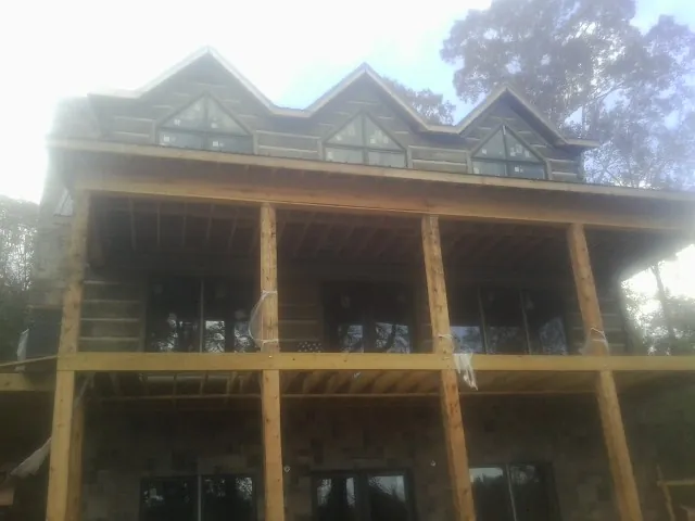 Dormers and porch framing on a large log home under construction — Roof Coating work by our crew in Greenville